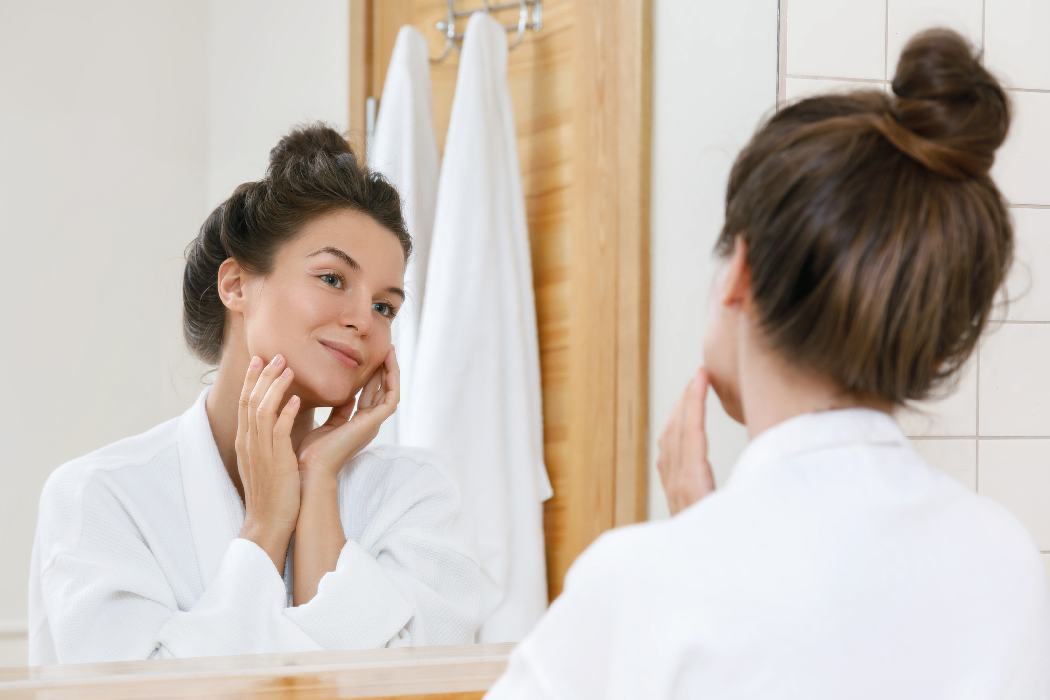 Young woman is looking into the mirror at morning